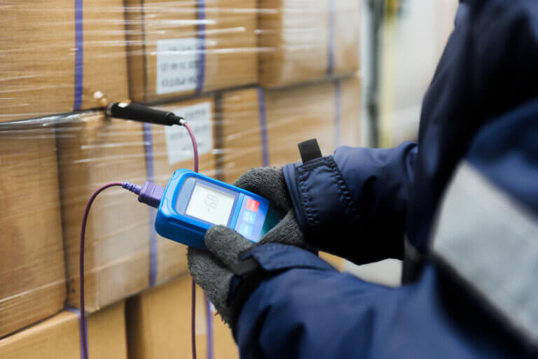 Hand of worker using thermometer to temperature measurement in the boxes.